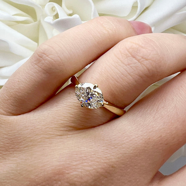 Diamond ring on a hand with white flowers in the background