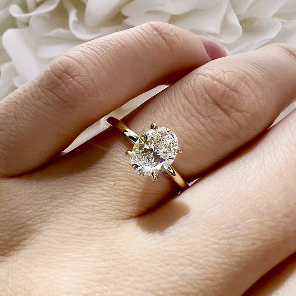 Gold ring with a large diamond on a hand against a soft white background