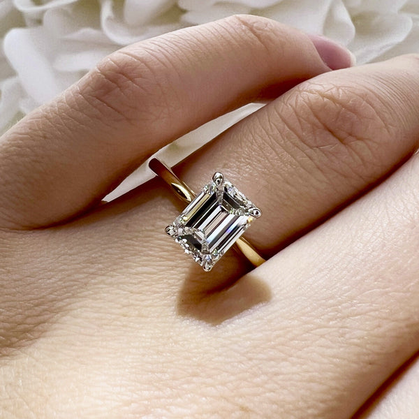 Diamond ring on a finger with a soft white fabric background