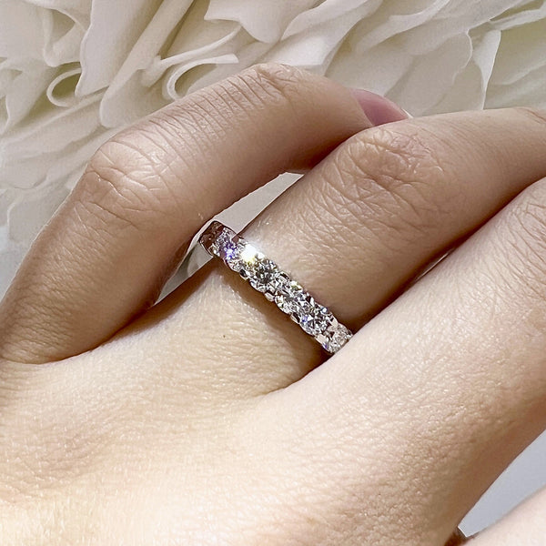 Silver ring with a purple gemstone on a hand against a textured white background