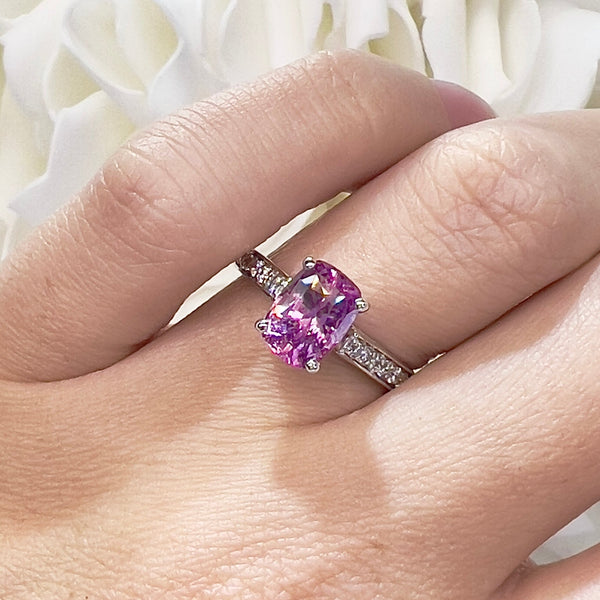 Pink gemstone ring on a hand with a white floral background