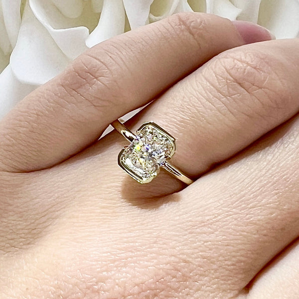 Gold ring with a diamond on a hand against a white floral background