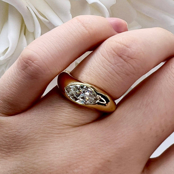 Gold ring with a diamond on a hand against a white floral background