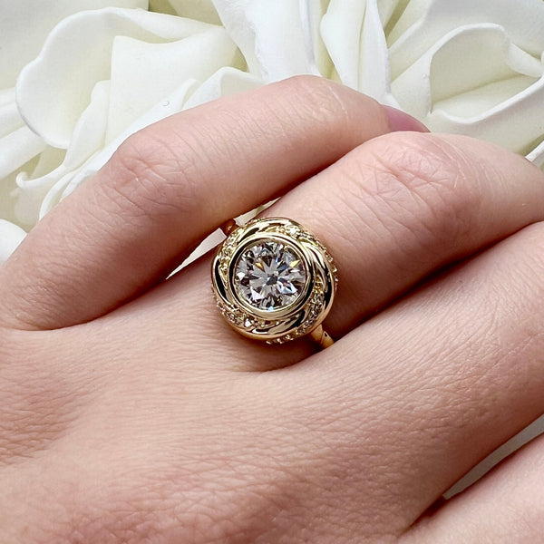 Gold ring with a large diamond on a hand against a white floral background