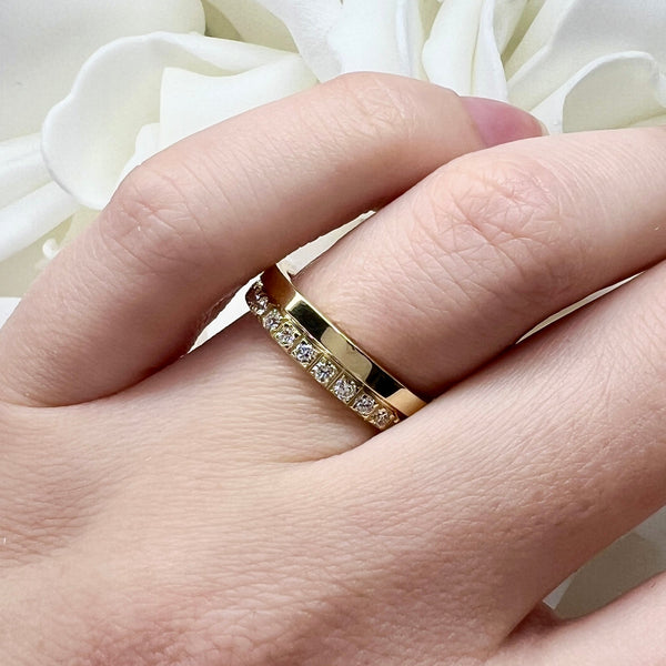 Gold ring with diamonds on a hand against a white floral background